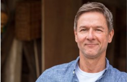 middle aged man with grey hair, smiling at the camera